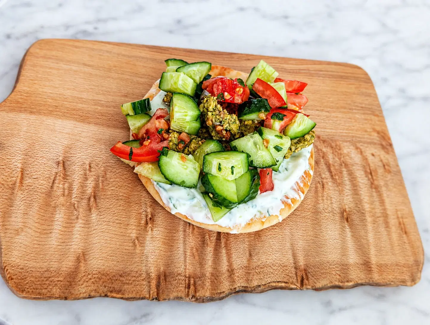 Baked falafel pitas filled with chickpea falafel, cucumber tomato salad, parsley, lemon, and homemade tzatziki.